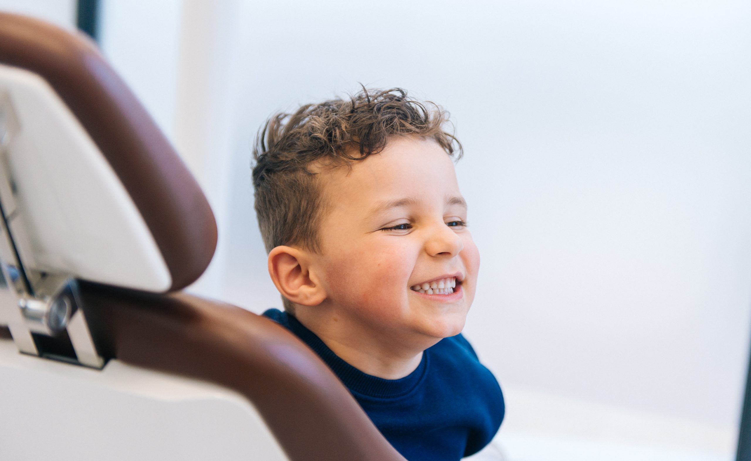 Een van onze kleine patiënten in de behandelstoel met een brede glimlach op zijn gezicht