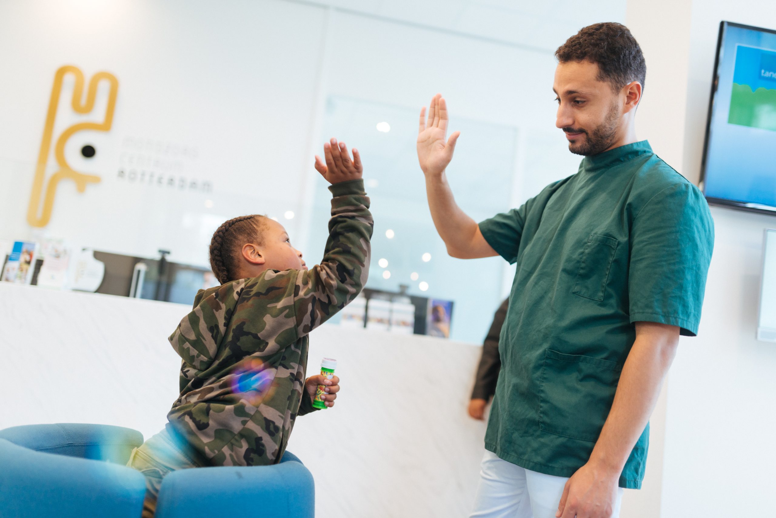 Een van onze tandartsend die een high-five geeft aan een jonge patiënt.